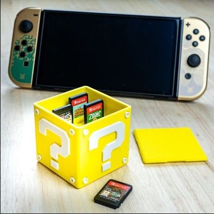 Caja impresa en 3D abierta con cartuchos de Nintendo Switch ordenados en sus separadores
